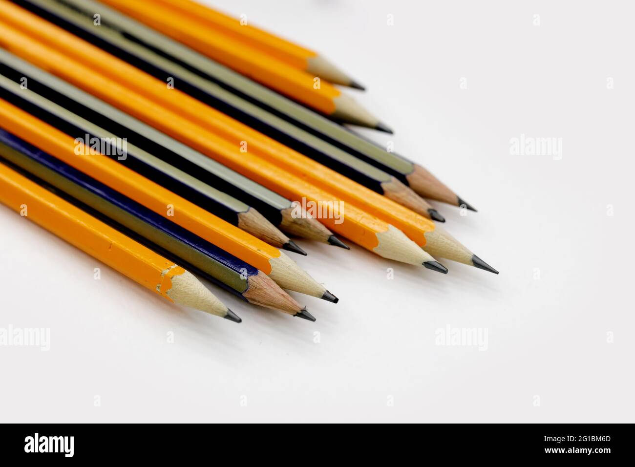 Wenige scharf geschärfte Bleistifte unterschiedlicher Farbe auf dem weißen Tisch Stockfoto