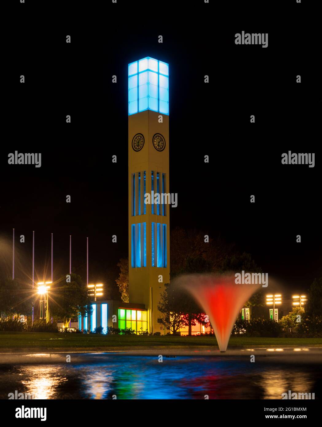 Palmerston North leuchtet in der Nacht, und die Hauptuhr im Zentrum der Stadt gibt eine farbenfrohe Show ab. Stockfoto
