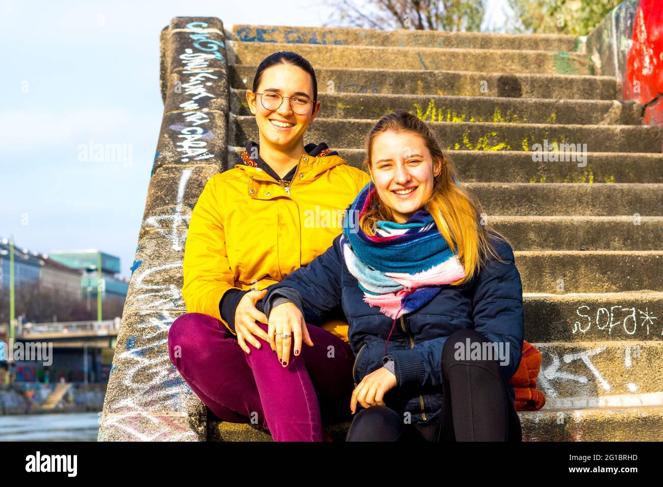 Die beiden niedlichen Mädchen, die auf der Treppe sitzen und die Kamera anlächeln, Österreich Stockfoto