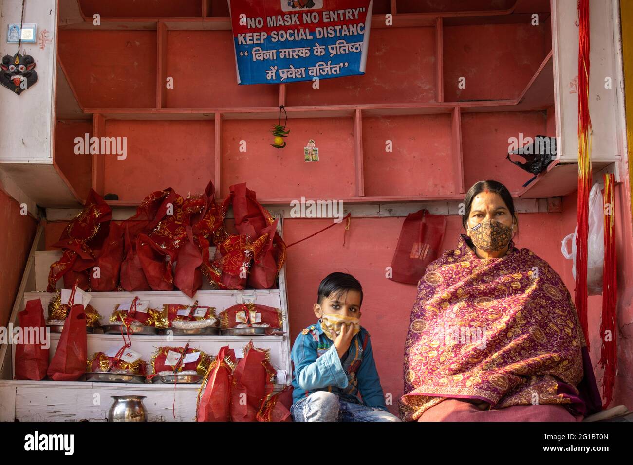 Haridwar, Uttarakhand, Indien, 14. April 2021.Indische Kauffrau mit ihrem Kind im Geschäft, das religiöse Materialien in Haridwar Uttarakhand Indien verkauft. Hochwertige Fotos Stockfoto