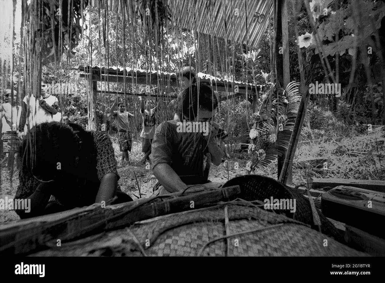 Sungai Uluk Palin, Kapuas Hulu, West Kalimantan, Indonesien. März 2007. Männer trauern, als sie das Grab des ehemaligen traditionellen Chefs der traditionellen Dayak Tamambaloh-Gemeinde besuchen, die in einem Langhaus im Dorf Sungai Uluk Palin (Sungulo Palin) lebt. Dies ist Teil einer Reihe traditioneller Veranstaltungen, die zu Ehren des ehemaligen traditionellen Chefs abgehalten wurden, der einige Wochen zuvor verstorben war. - Fotografiert auf Schwarz-Weiß-Film, gescannt, digitalisiert. Stockfoto