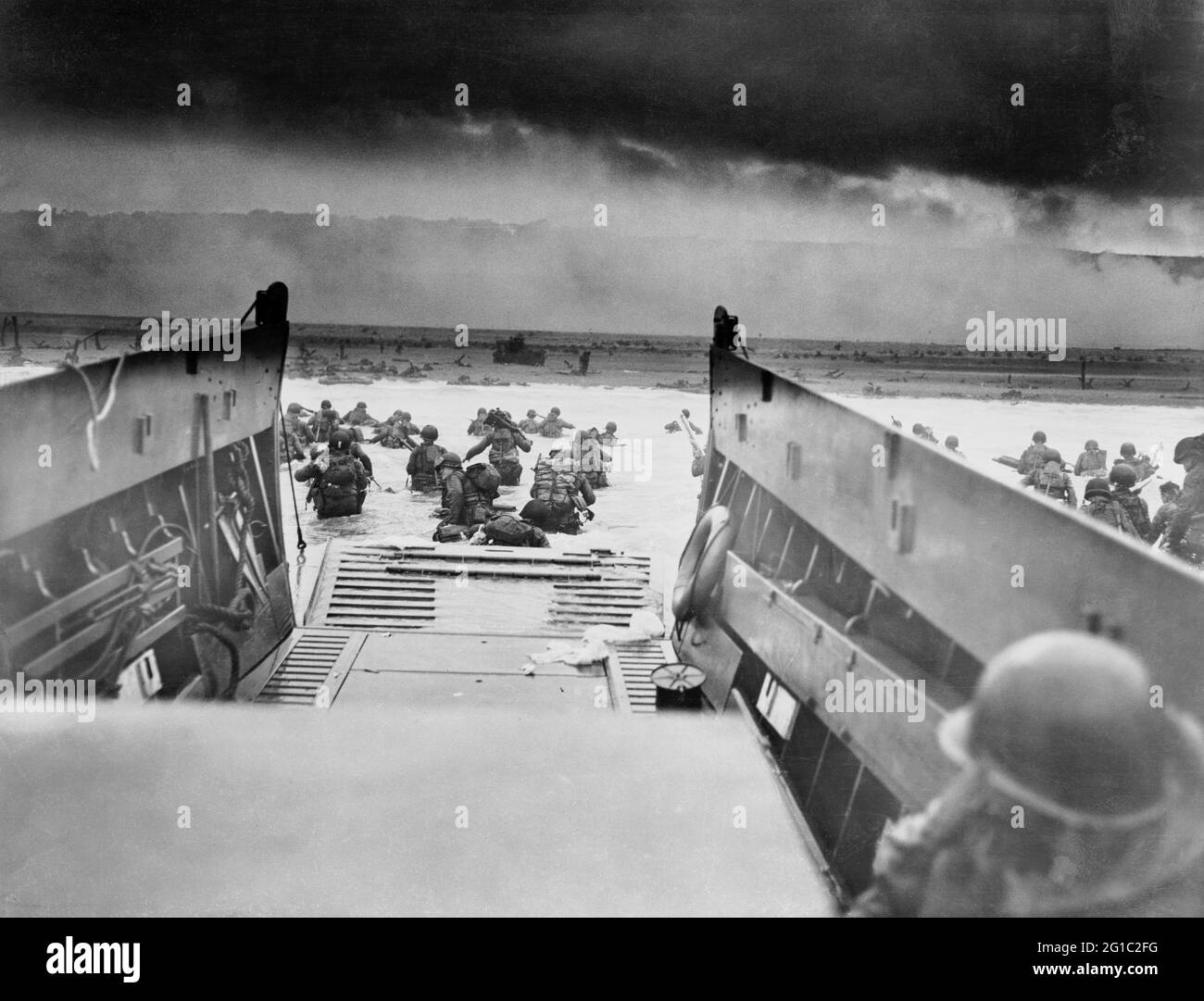 Restauriertes Foto, das amerikanische Soldaten zeigt, die am D-Day, 6. Juni 1944, vom Landungskahn der Küstenwache in Richtung Strand in der Normandie wateten. Sargent, Robert F., 1923-2012, Fotograf. Stockfoto