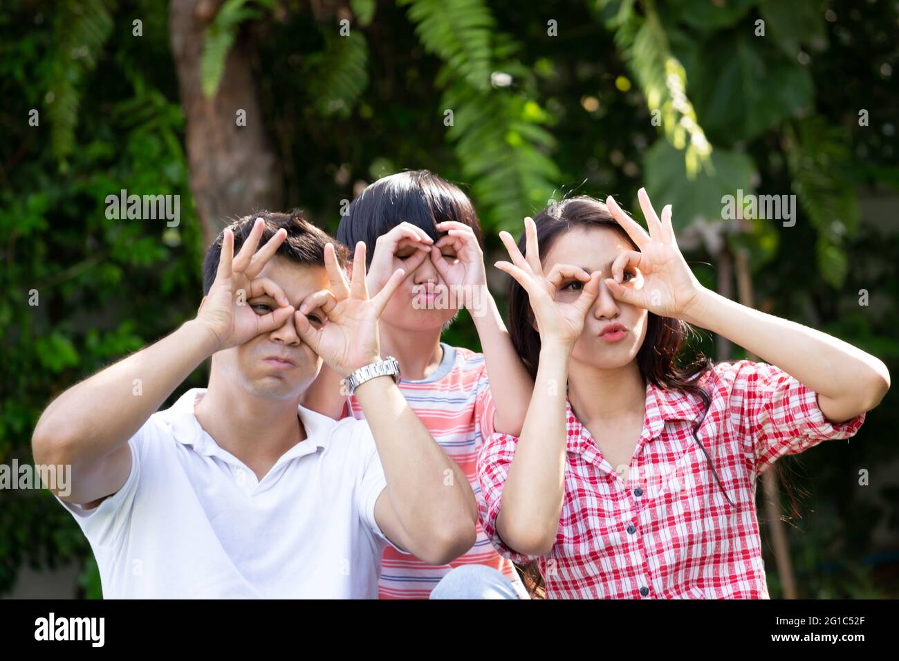 Glückliche Familie, die lustige Gesichter macht und Spaß mit den Fingern Brillen hat. Familie Freizeit spielen Tricks Narr Konzept Stockfoto