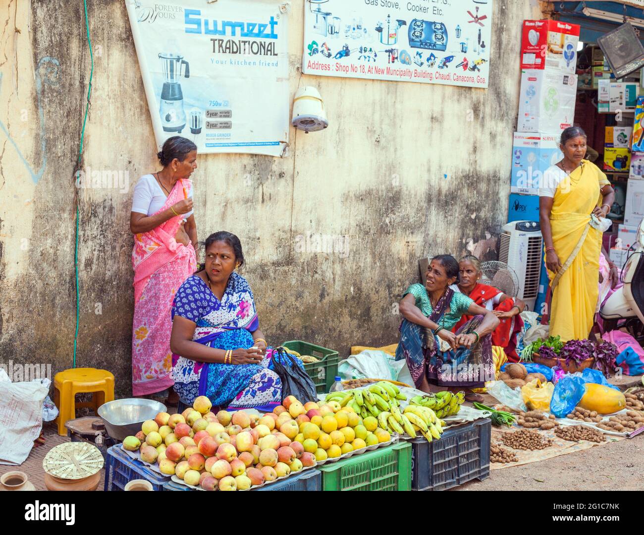 Indische Markthändlerinnen, die Äpfel, Bananen, Orangen und Gemüse vom Straßenstand in Chaudi (Canacona), Goa, Indien, verkaufen Stockfoto