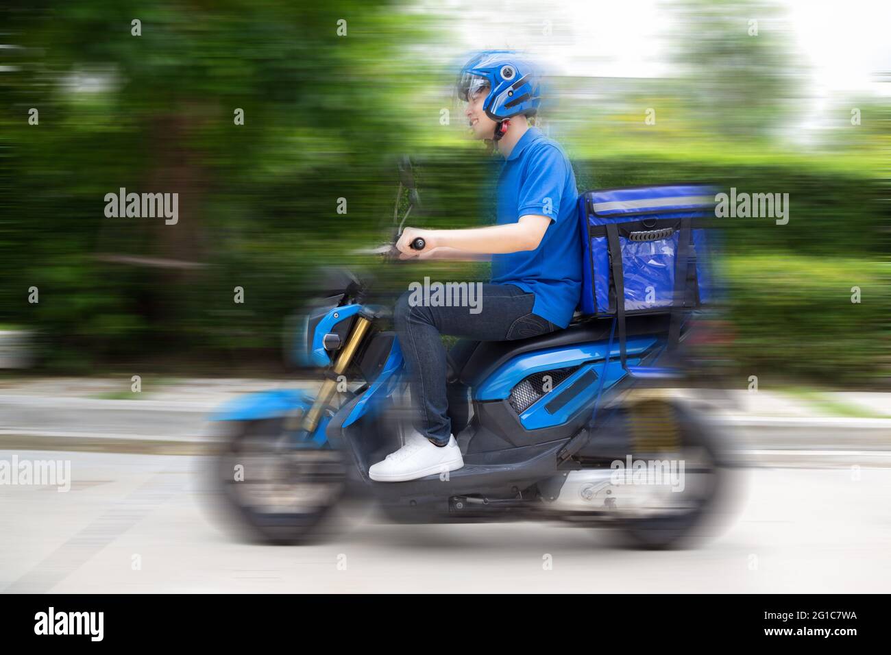 Delivery Mann trägt blaue Uniform Reiten Motorrad und Lieferkarton. Motorrad liefert Food Express Service-Konzept Stockfoto