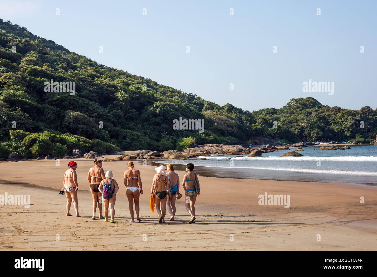 Eine Gruppe von ausländischen Touristen mittleren Alters, die an einem idyllischen, einsamen Strand entlang gehen, Agonda, Goa, Indien Stockfoto