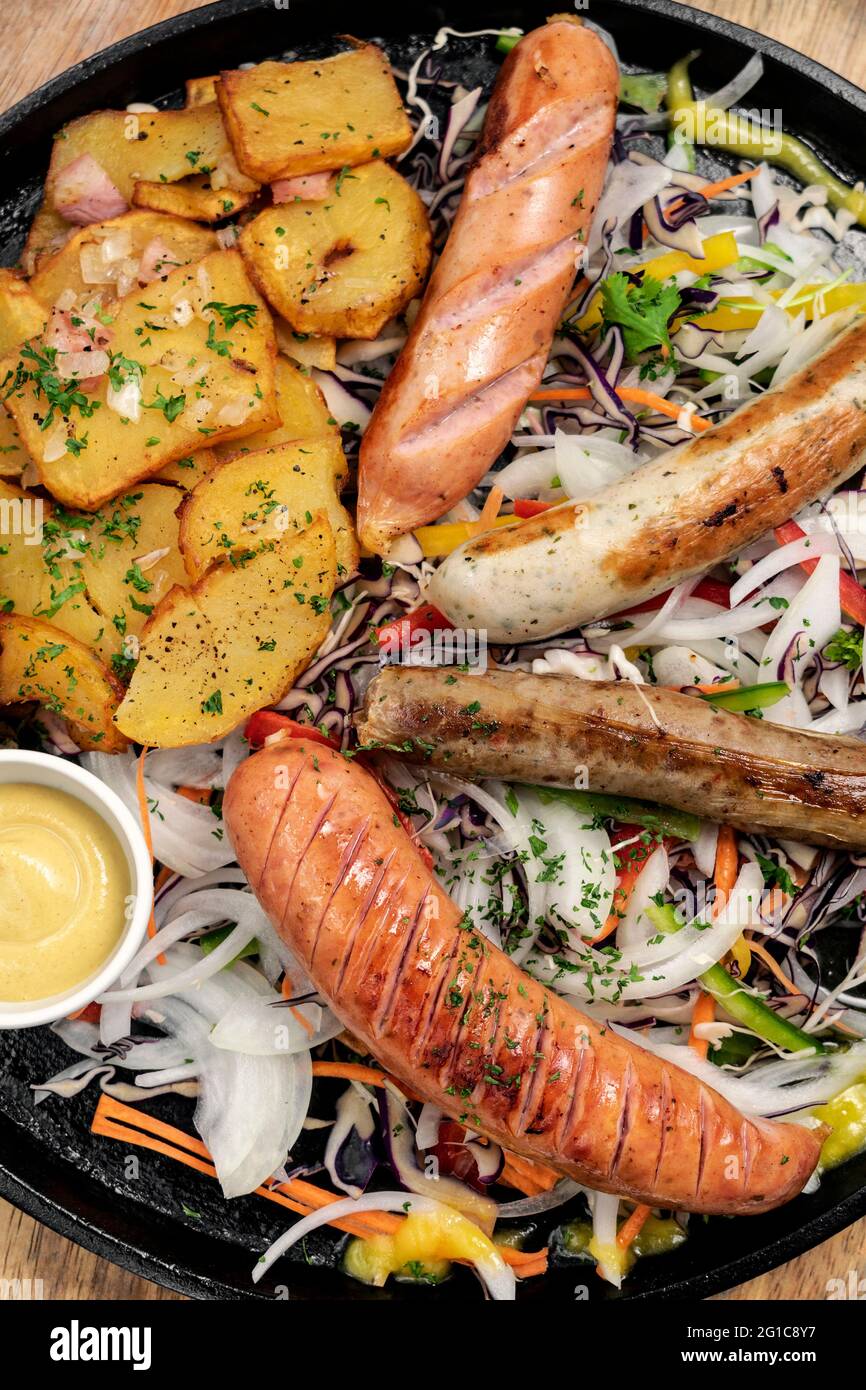 Gemischte deutsche traditionelle Bio-Wurst- und Kartoffelmahlplatte mit Nurenberger, Lamm und Schweinefleisch mit Salat und Senf Stockfoto