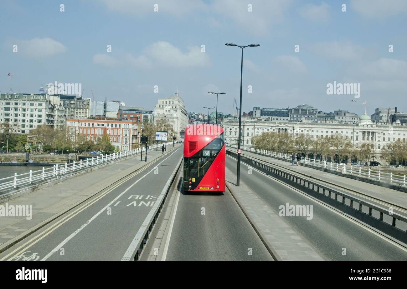 London, Großbritannien - 21. April 2021: Ein roter Doppeldeckerbus, der an einem sonnigen Morgen in London über die Waterloo Bridge nach Aldwych fährt. Somerset House i Stockfoto