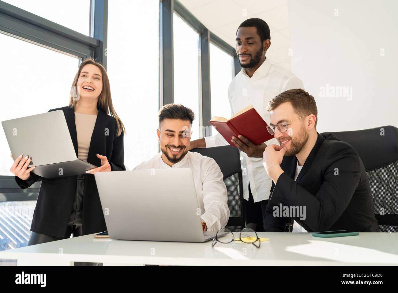 Fröhliches Geschäftsteam, das an Laptops an einem neuen Projekt arbeitet Stockfoto