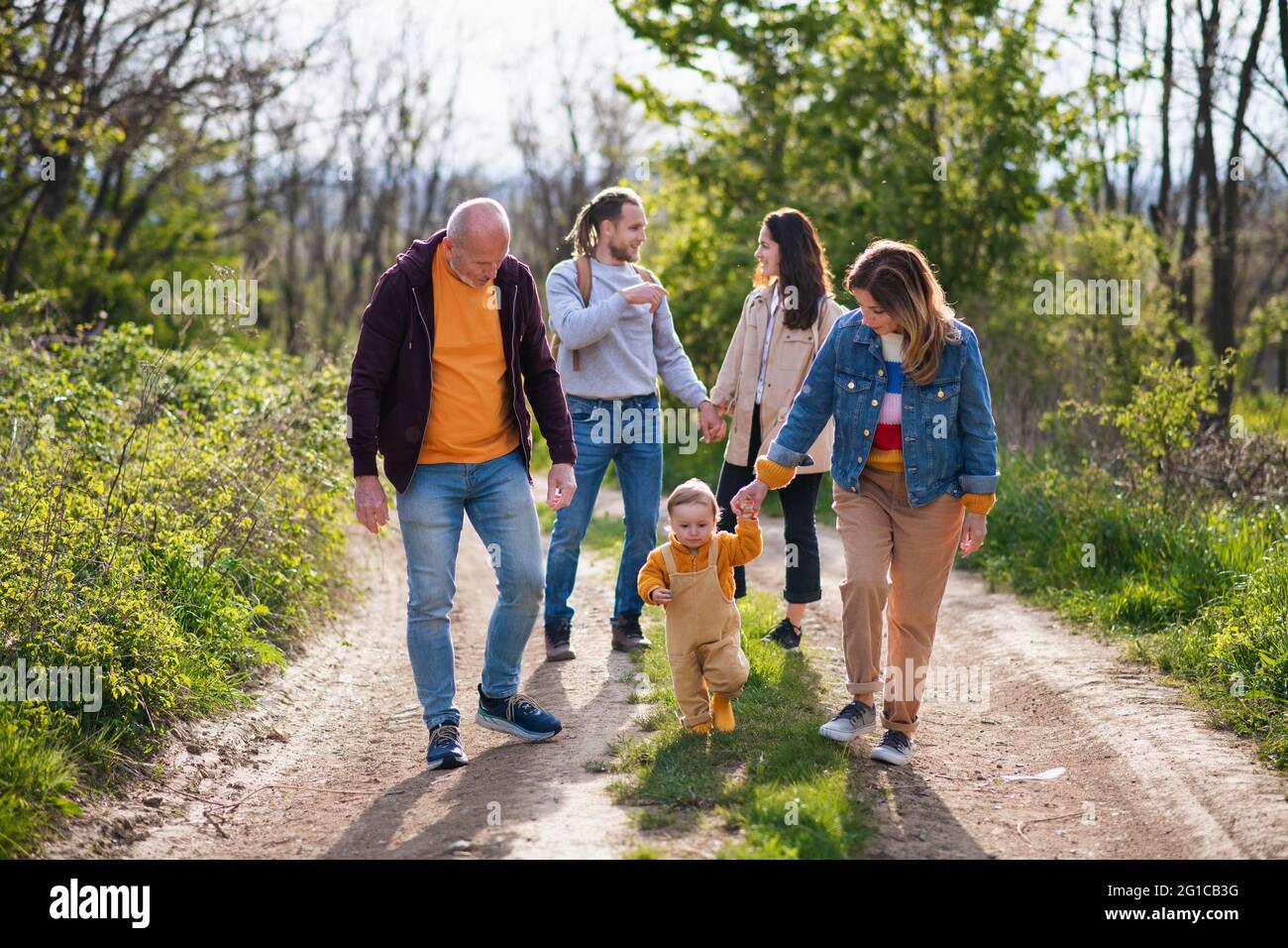Kleines Kleinkind mit Eltern und Großeltern auf einem Spaziergang im Freien in der Natur. Stockfoto