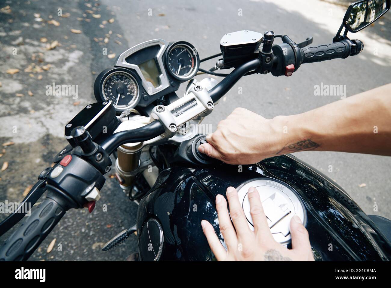 Mann, der den Benzinstand im Motorradöltank überprüft Stockfoto