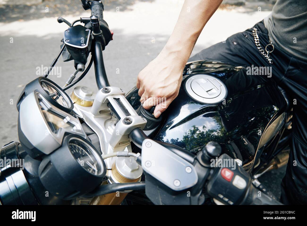 Nahaufnahme des Mannes, der den Motorradöltank öffnet, um Benzin zu tanken Stockfoto