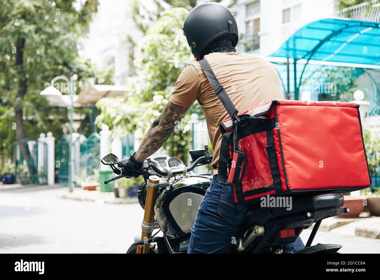 Kurier mit großem Thermobeutel, der auf dem Motorrad fährt, wenn er Lebensmittel an Kunden liefert Stockfoto