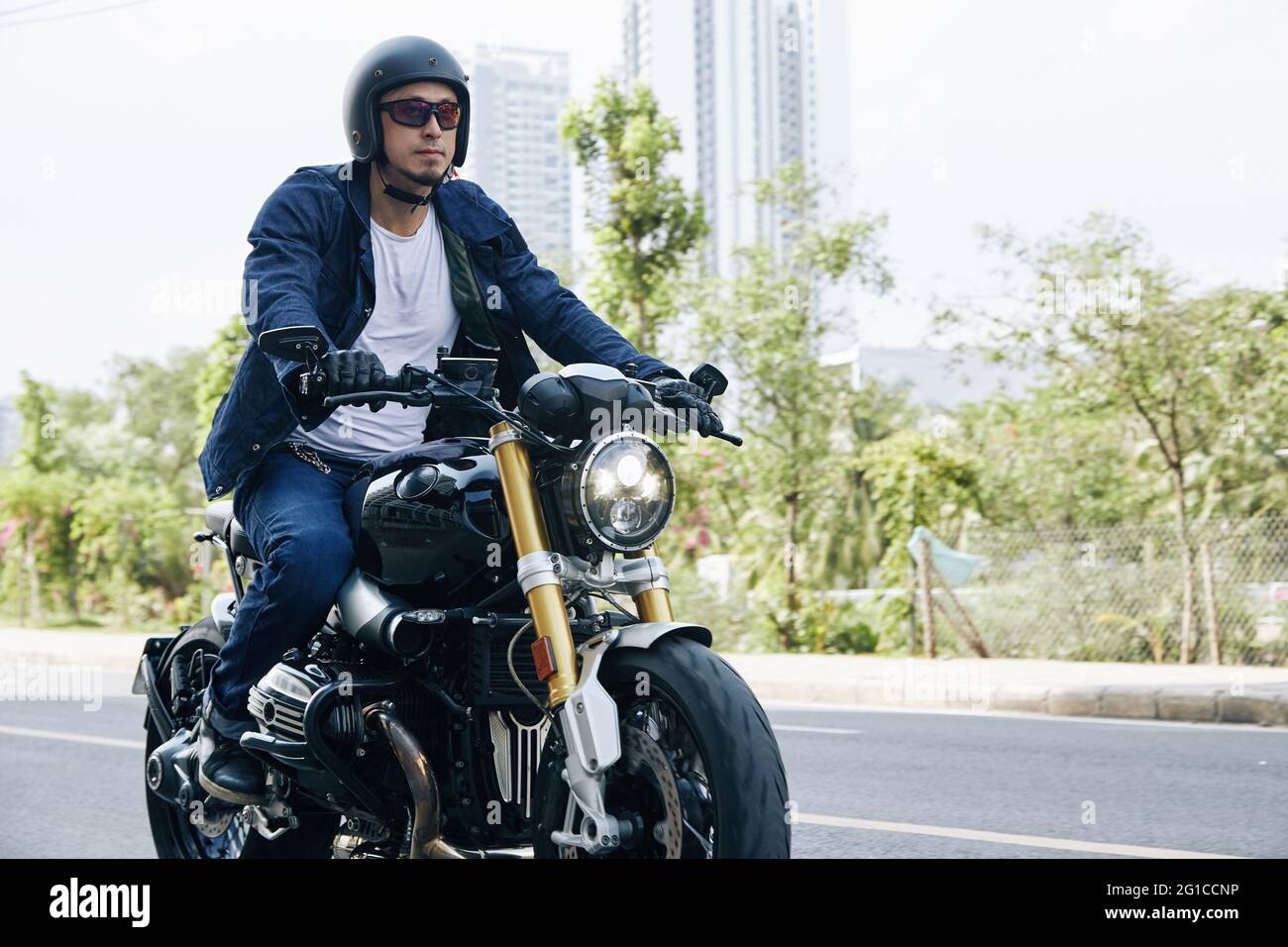Mann in Sonnenbrille und Helm, der schnell auf dem Motorrad auf der Autobahn fährt Stockfoto