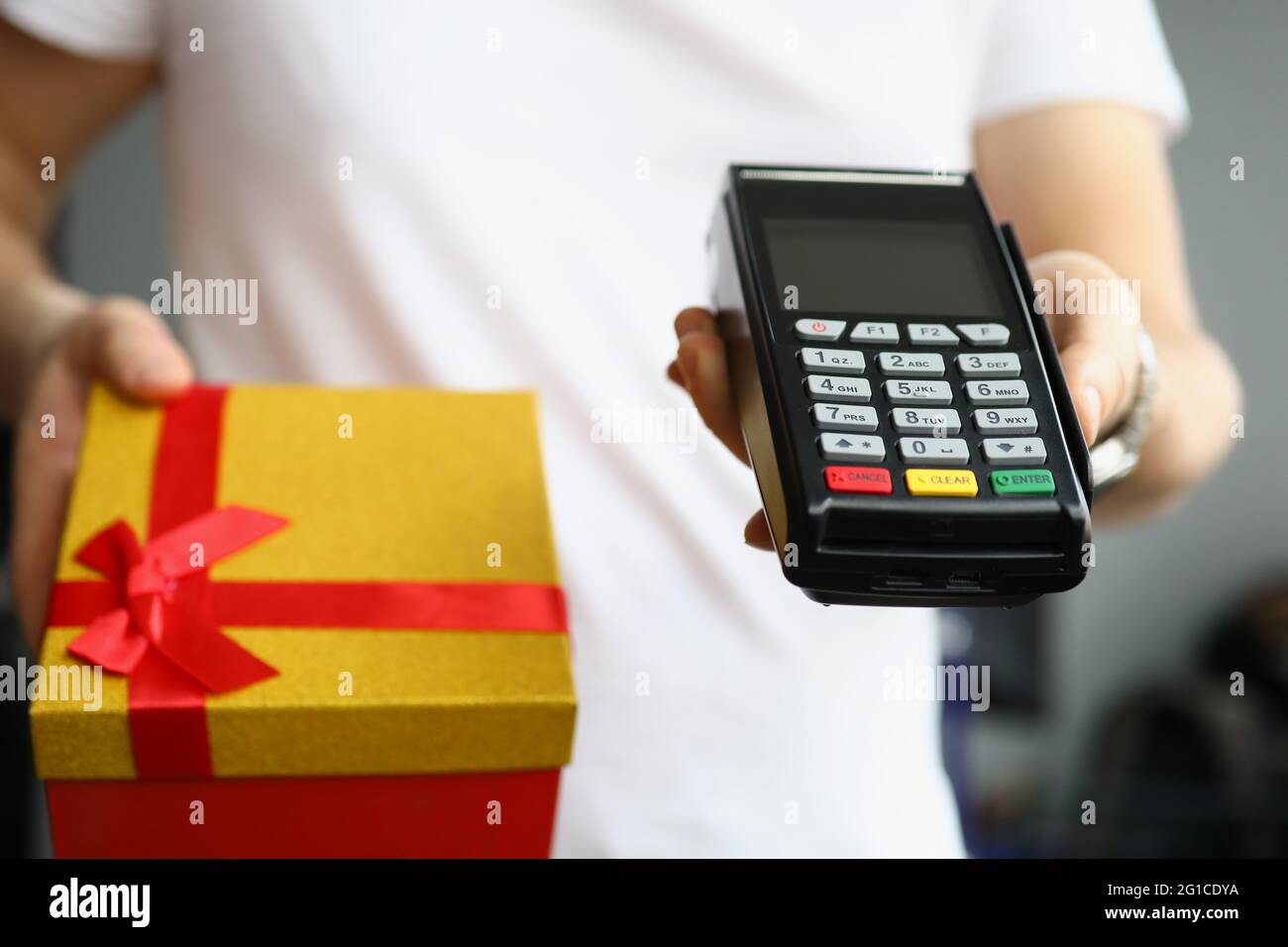Zahlung per Kreditkarte mit Plastikkarte am Terminal an Kurier mit Geschenkbox Stockfoto