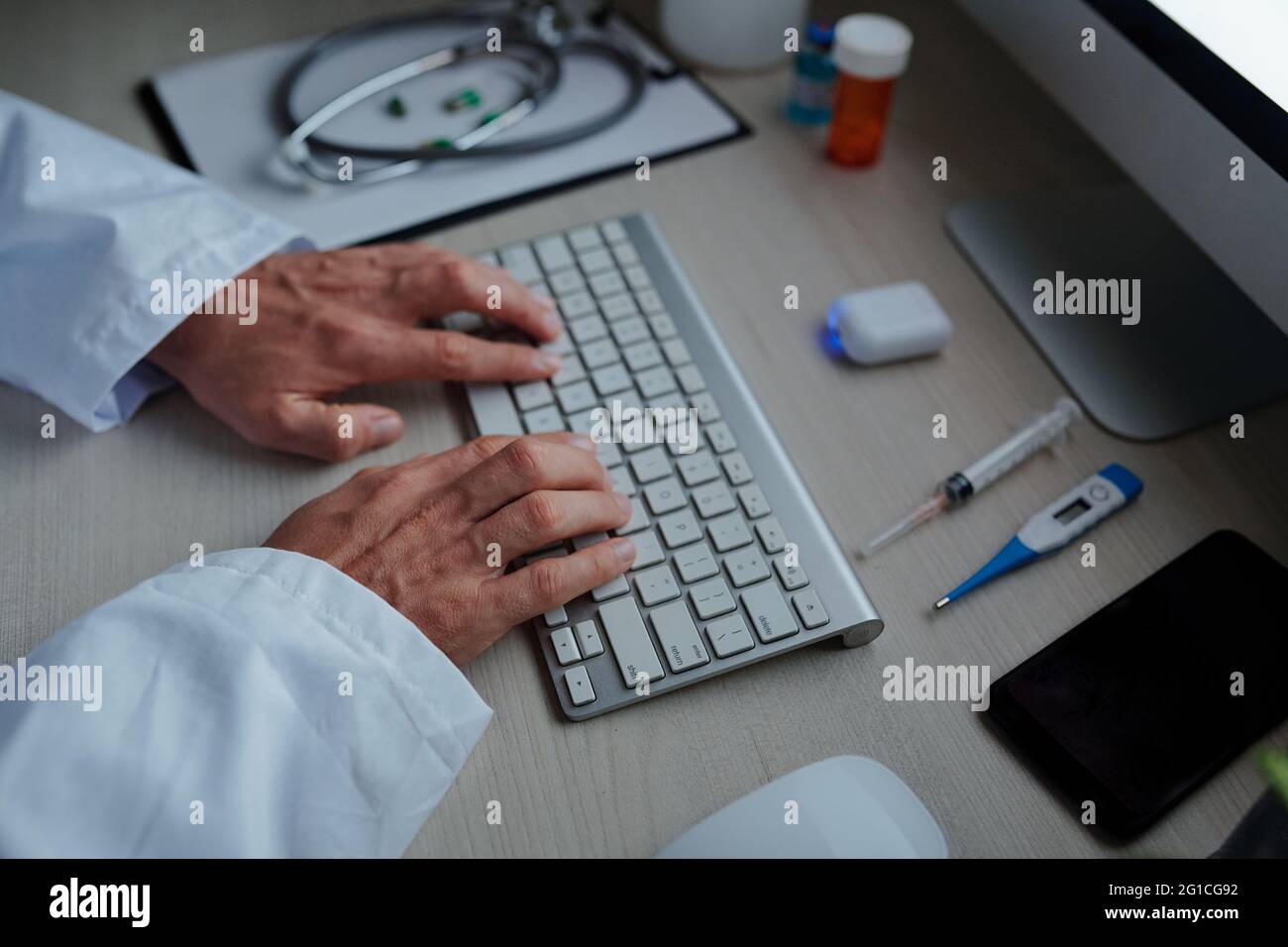 Hände eines Arztes, der am Computer arbeitet, nachdem er Runden gemacht und die Patienten am Morgen untersucht hat Stockfoto