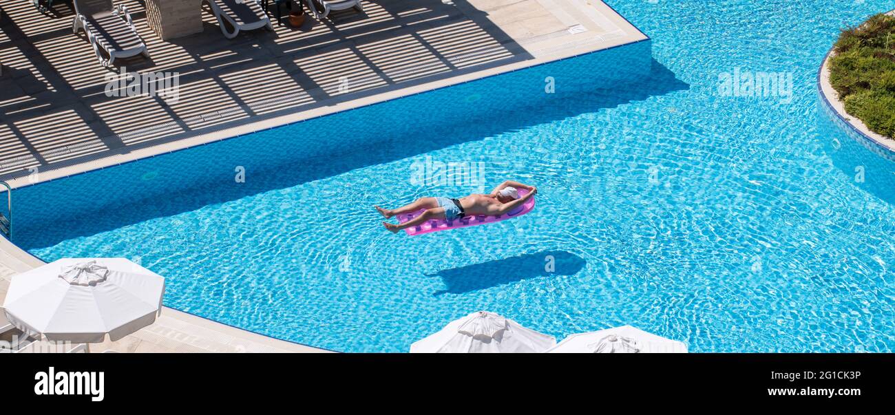 Antalya, Türkei-9. September 2017: Junger Mann, der an einem heißen Sommertag auf einer aufblasbaren Luftmatratze im Schwimmbad sonnenbaden kann. Touristen genießen Urlaub. Stockfoto
