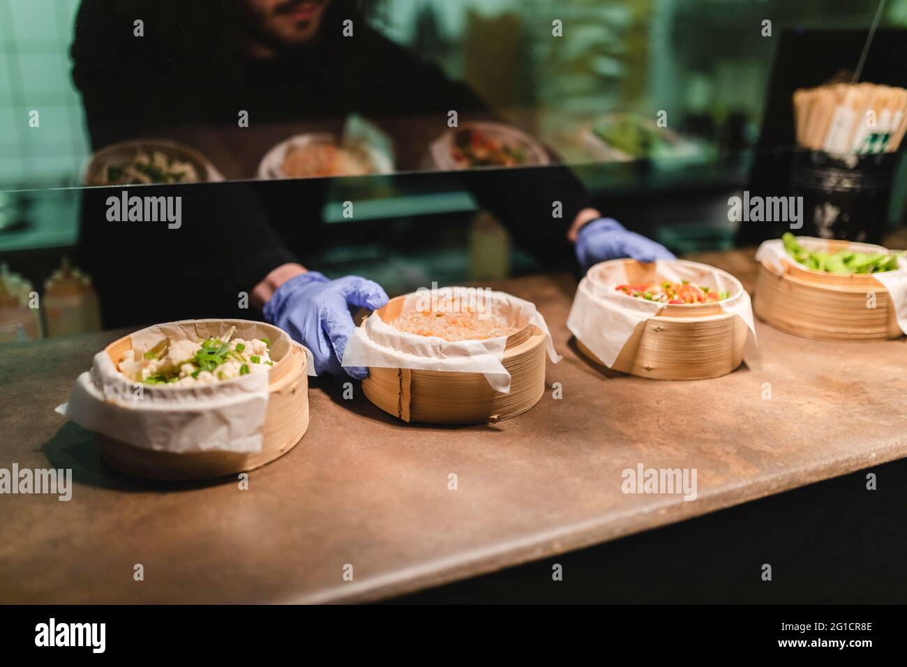 Männlicher Koch serviert Speisen in Holzschüsseln auf der Theke im Restaurant Stockfoto