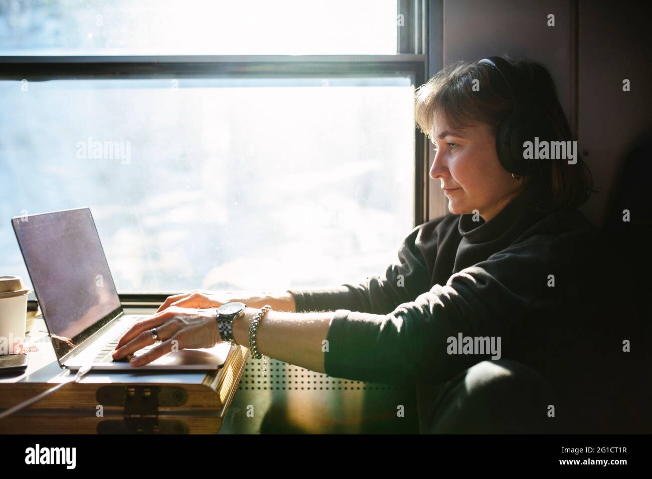 Geschäftsfrau mit Laptop, während sie am Fenster im Zug sitzt Stockfoto