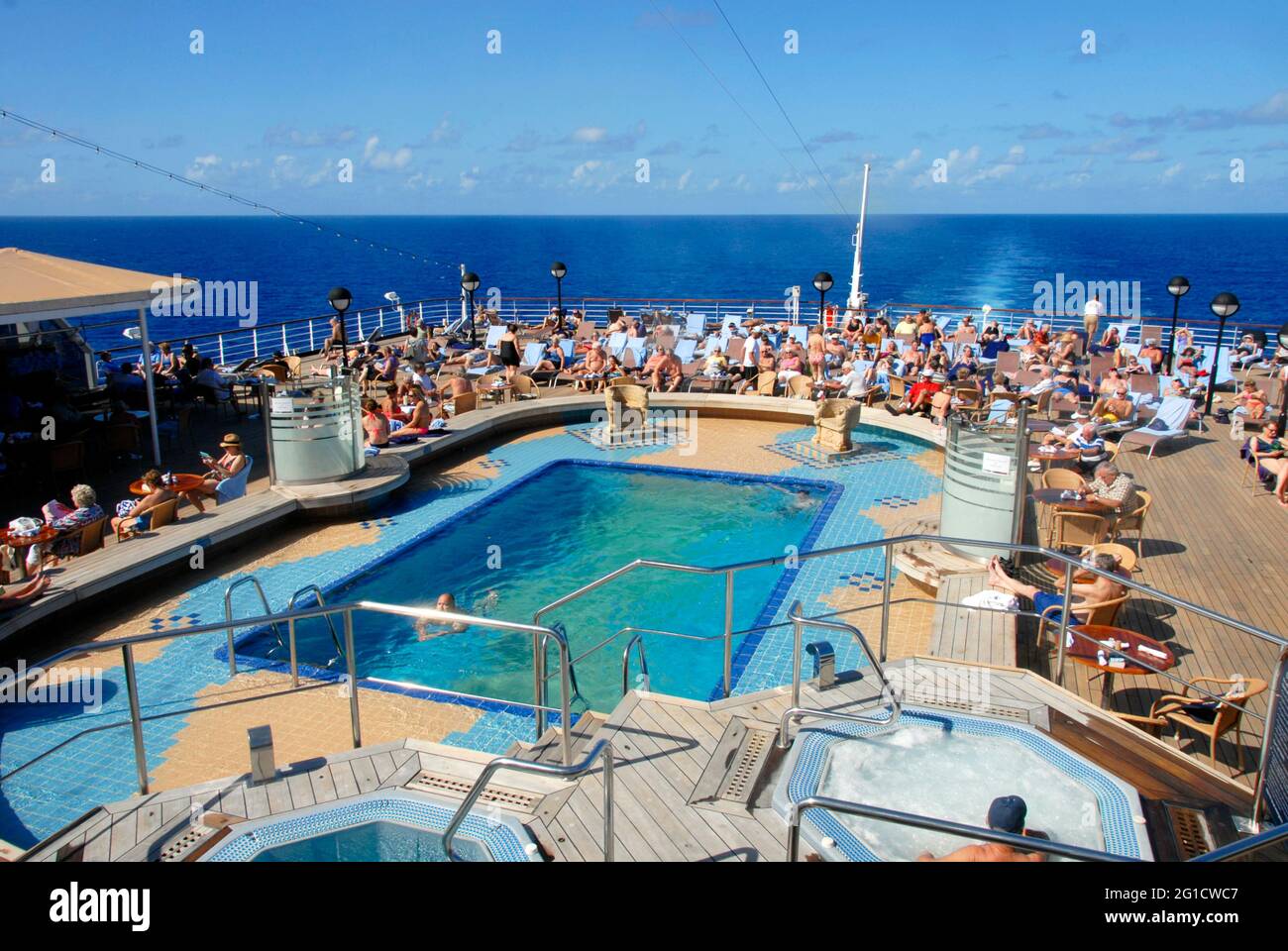 Das Schwimmbad am Heck eines Kreuzfahrtschiffes mit Menschenmassen beim Sonnenbaden, Karibik Stockfoto