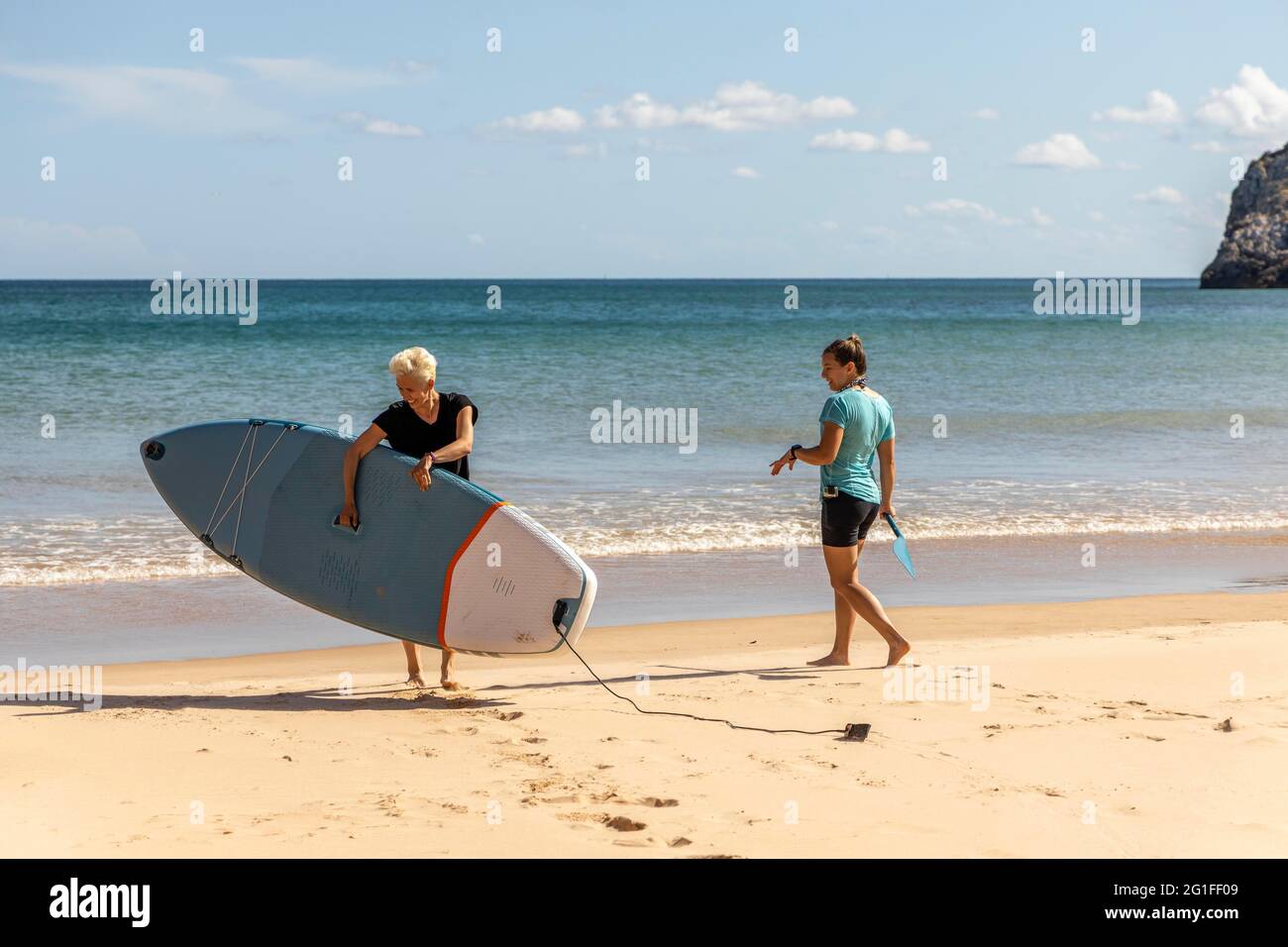 Zwei Freundinnen genießen Stand Up Paddling auf dem Atlantik Meer in Portugal Stockfoto