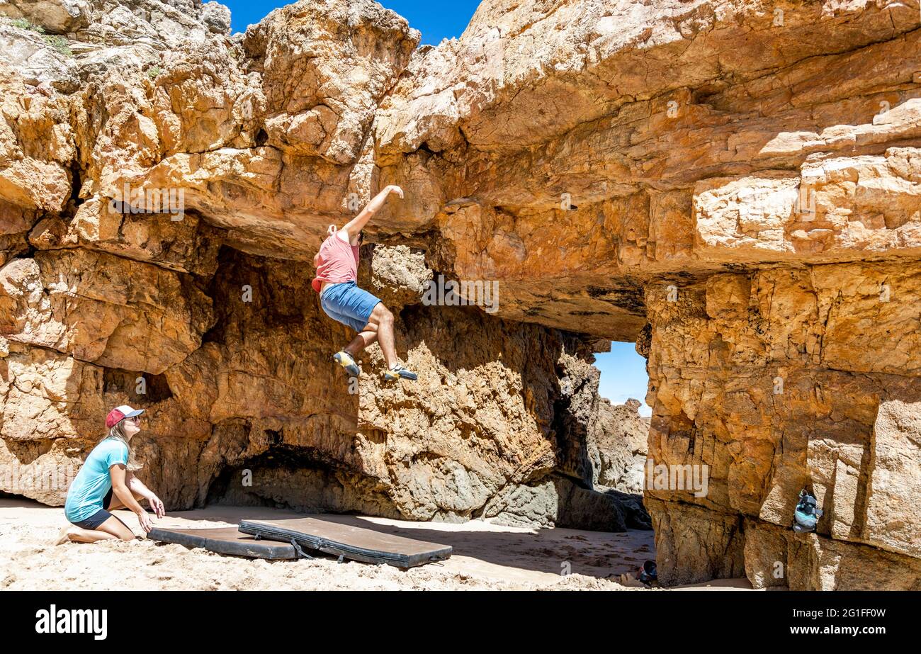 Ein Kletterer, der auf Sicherheitsmatten am Strand, Algarve, Portugal, vom Felsen fällt Stockfoto