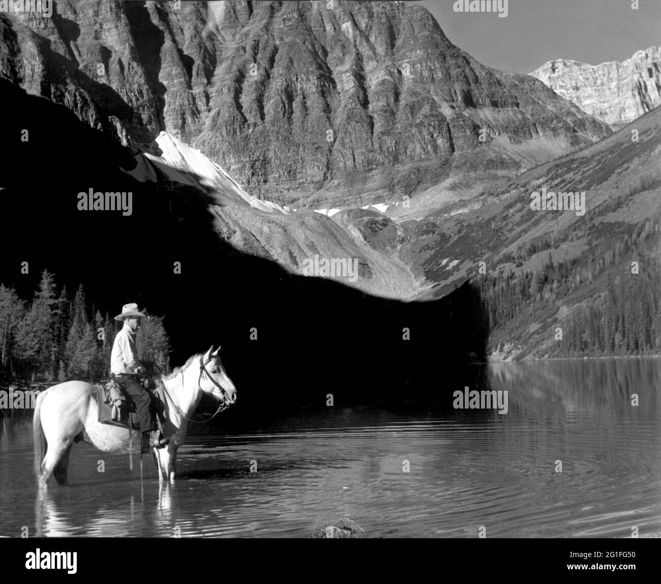 Geographie/Reisen, Kanada, Berge, Rocky Mountains, Alberta, Taylor Lake, Cowboy auf dem Pferd auf See, ZUSÄTZLICHE-RIGHTS-CLEARANCE-INFO-NOT-AVAILABLE Stockfoto