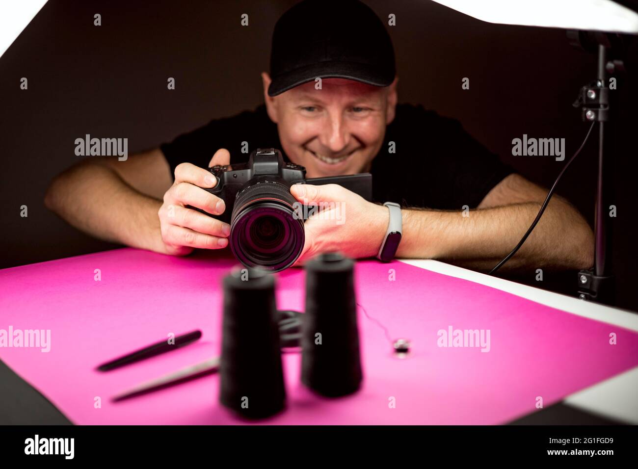 Ein Fotograf, der in ein Foto von schwarzen Schneiderzubehör aufgenommen hat Das Studio Stockfoto