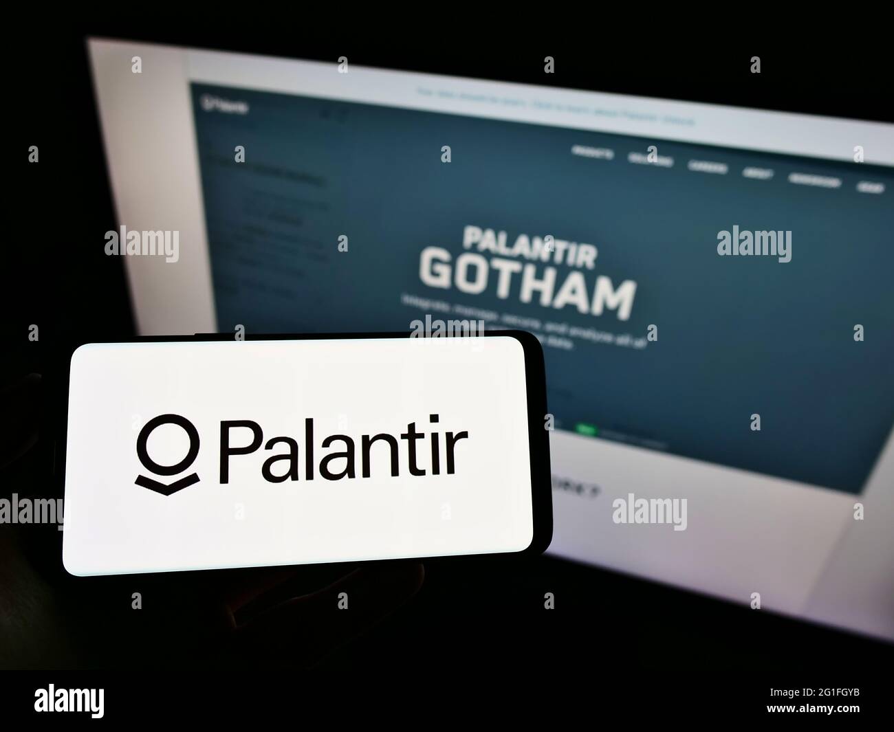 Person, die ein Mobiltelefon mit dem Logo des amerikanischen Softwareunternehmens Palantir Technologies Inc. Auf dem Bildschirm vor der Webseite hält. Konzentrieren Sie sich auf die Telefonanzeige. Stockfoto