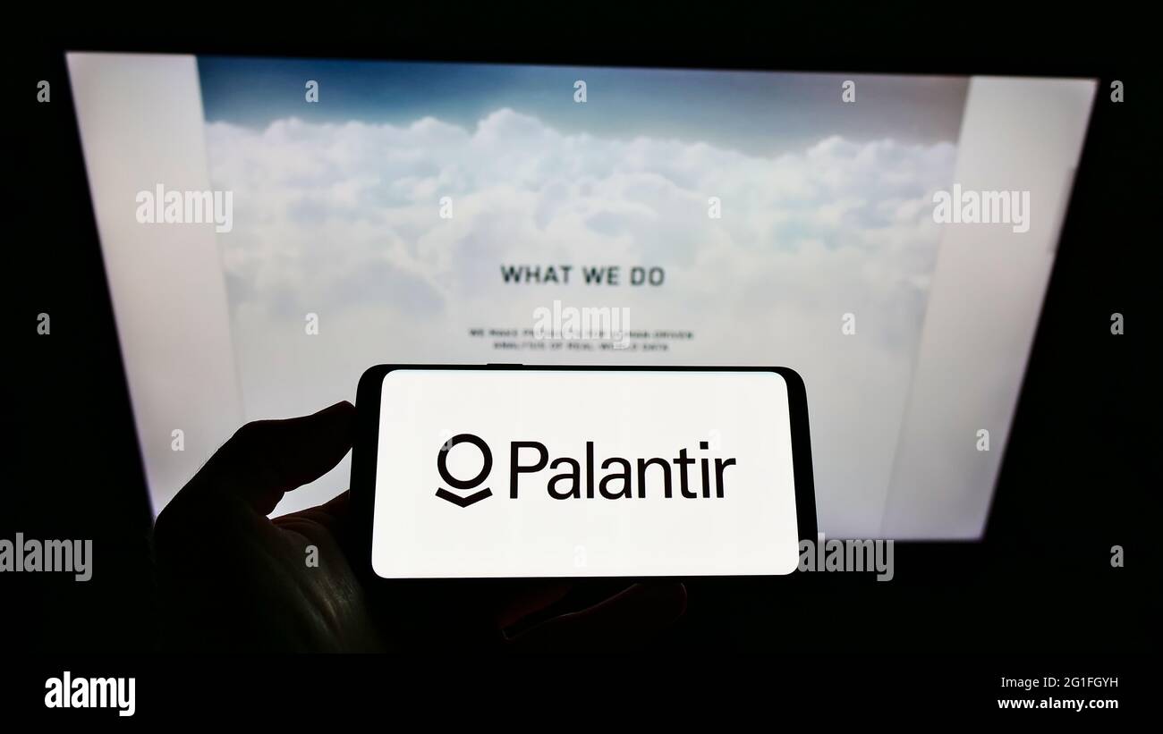 Person, die Mobiltelefon mit dem Logo des US-Softwareunternehmens Palantir Technologies Inc. Auf dem Bildschirm vor der Business-Webseite hält. Konzentrieren Sie sich auf die Telefonanzeige. Stockfoto