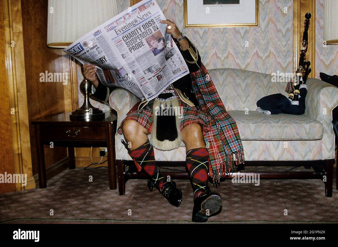 Scotsman Zeitung lesen, Couch, Sofa, Kilt, Tartan, Karierten. Sporran, Dudelsack, Edinburgh, Schottland, Großbritannien Stockfoto