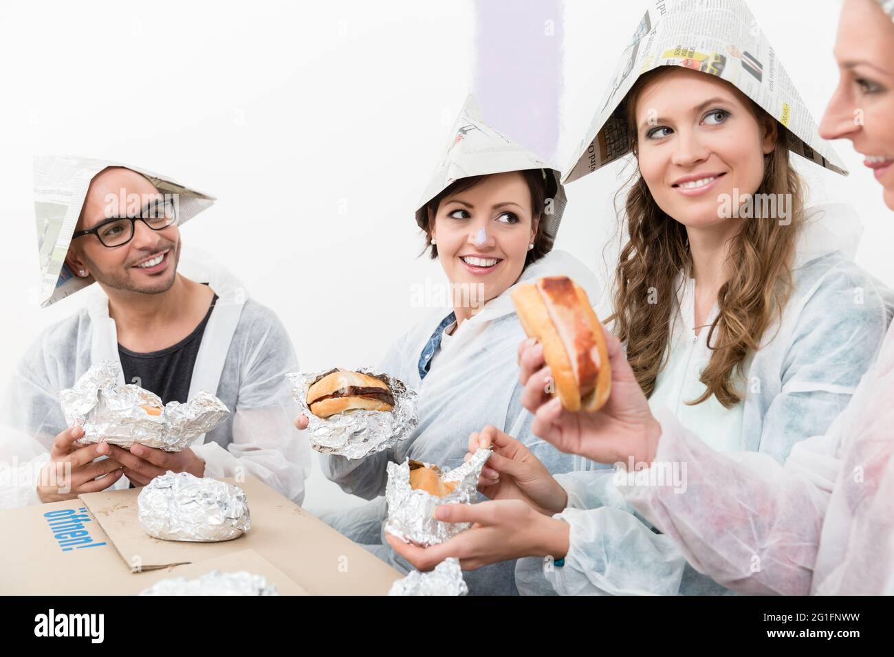Gerne Freunde das Tragen von Arbeitskleidung und Papier hat genießen die fast food im neuen Haus Stockfoto
