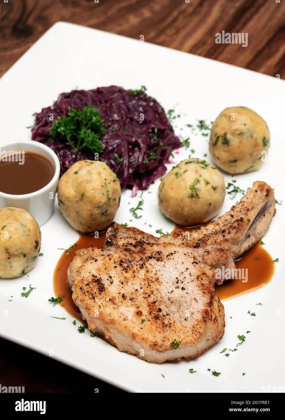 gegrilltes Schweinekotelett im deutschen Stil mit Brotknödeln und Rot Traditionelle Kohl-Mahlzeit auf dem Holztisch Stockfoto