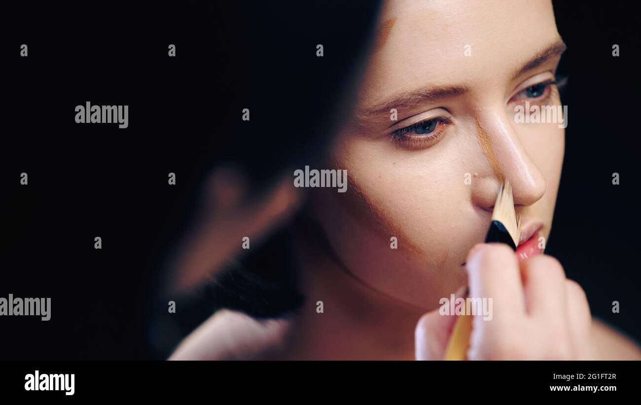 Verschwommener Make-up-Künstler macht konturierende Gesicht der Frau mit kosmetischen Pinsel Stockfoto