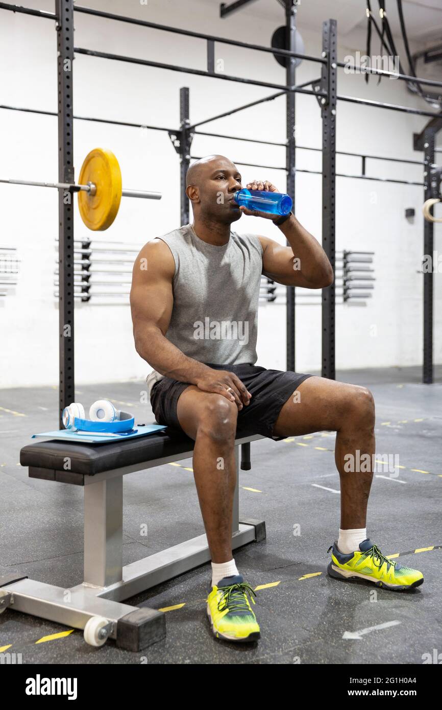 Schwarzer männlicher Athlet trinkt nach dem Training im Fitnessstudio Wasser. Sport und gesunder Lebensstil. Stockfoto