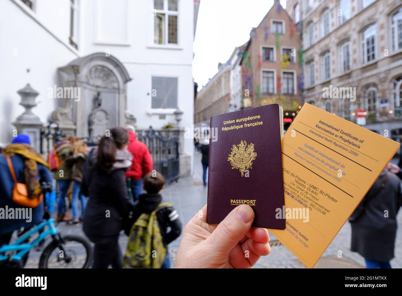 Belgien, Brüssel, 19. Februar 2021: Französischer Reisender mit seinem Reisepass und einem internationalen Impfpass oder Prophylaxe-Zertifikat in einer Straße von B Stockfoto