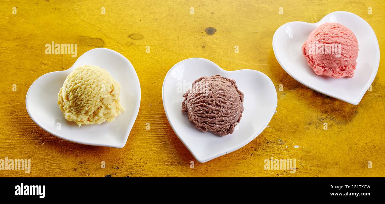 Von oben Komposition aus bunten Vanille und Schokolade und Erdbeer-Eisschaufeln in herzförmigen Schalen serviert Stockfoto