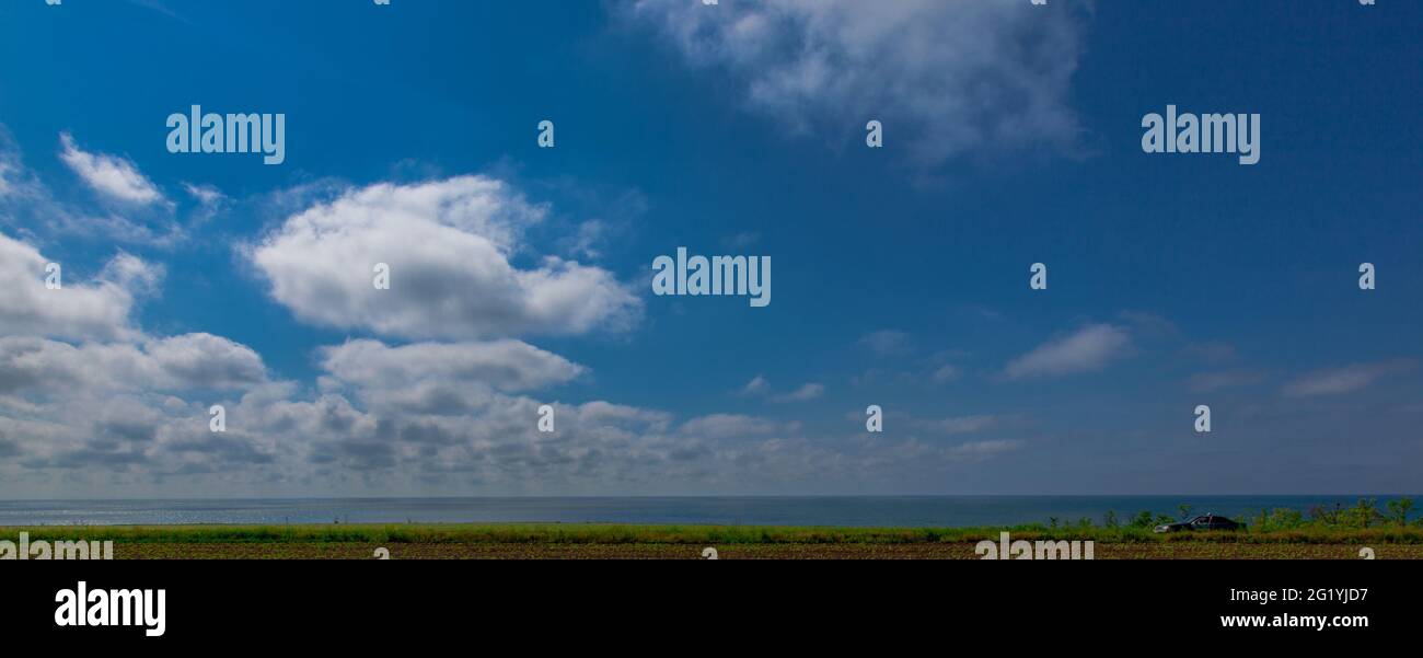 Ländliches Feld am Meer und das Auto blieb auf der Straße stehen Stockfoto