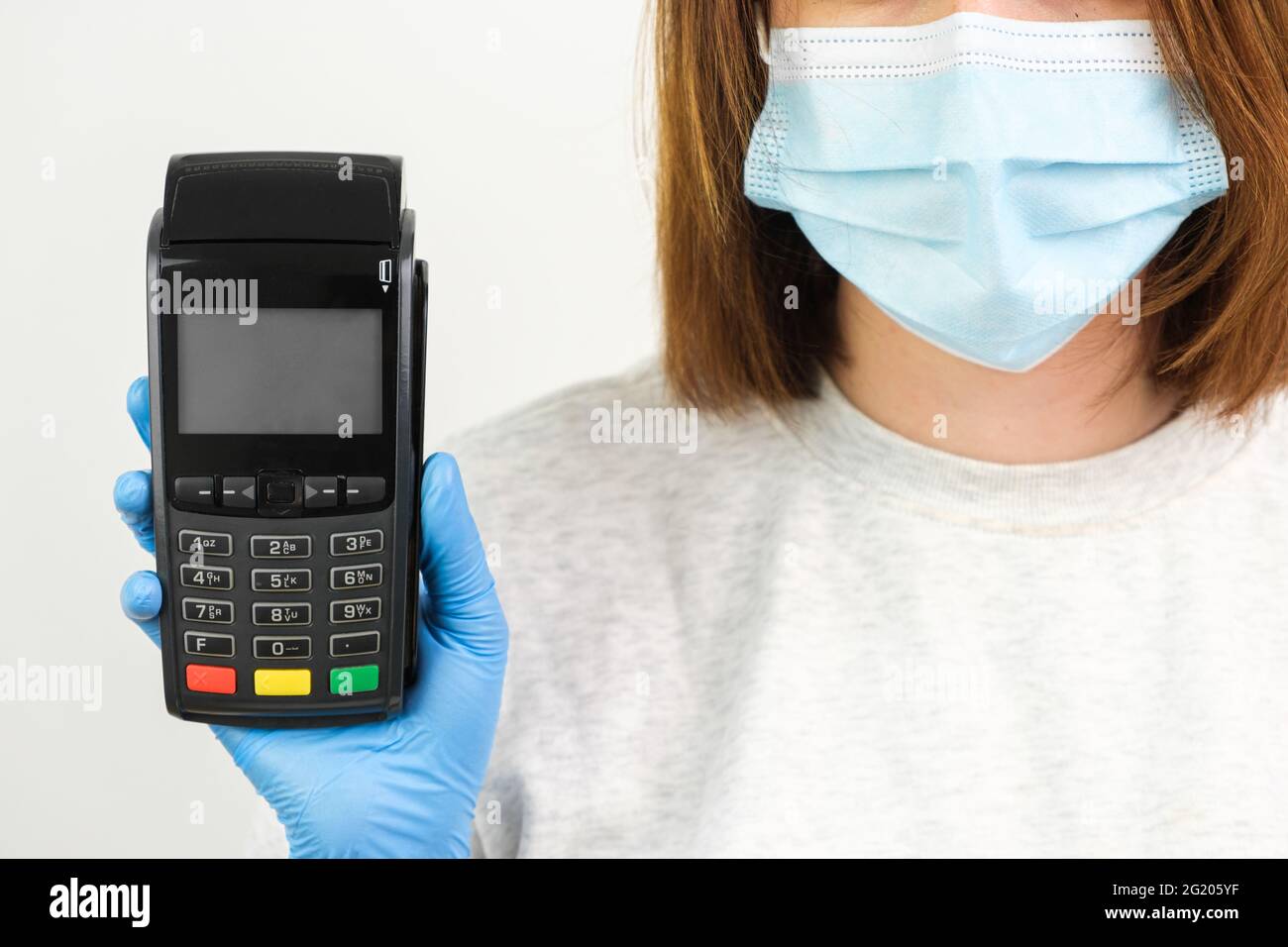 Frau in Gummihandschuhen und Gesichtsmaske mit einem POS-Terminal für die Zahlung während einer Pandemie des Coronavirus Stockfoto
