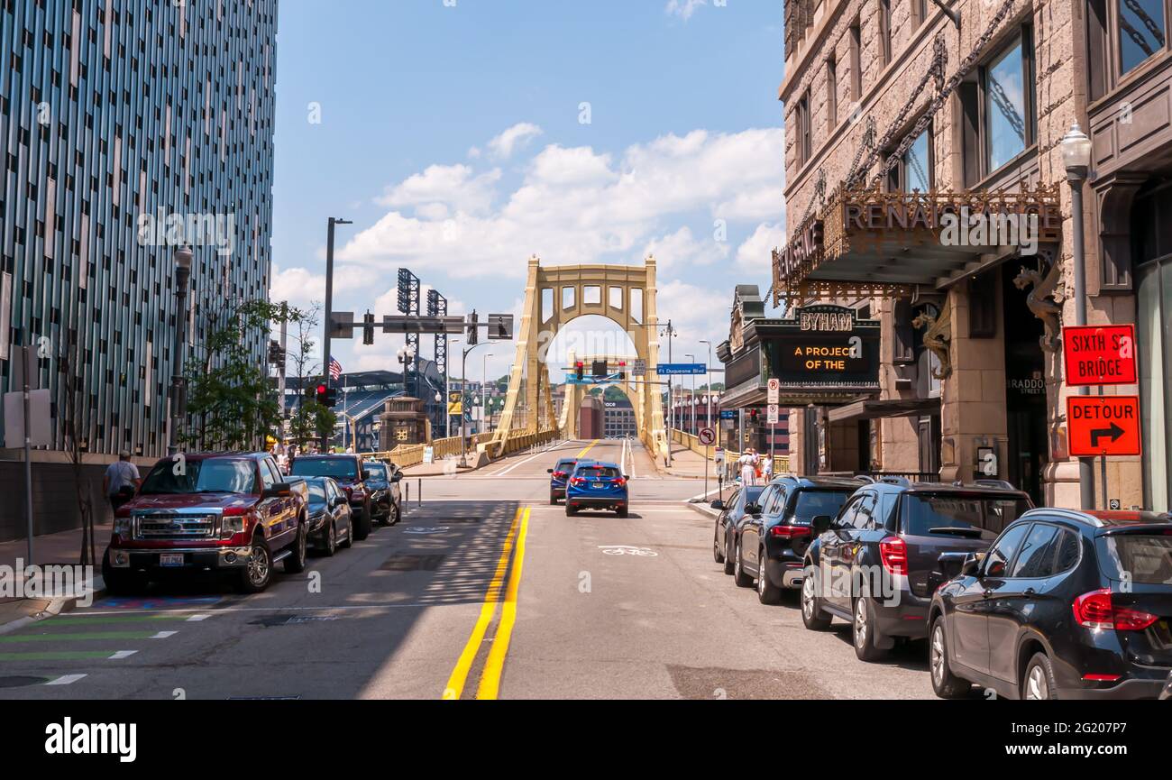 Geparkte Autos und Gebäude entlang der 6. Straße, die zur Roberto Clemente Brücke in der Innenstadt von Pittsburgh, Pennsylvania, USA führt Stockfoto