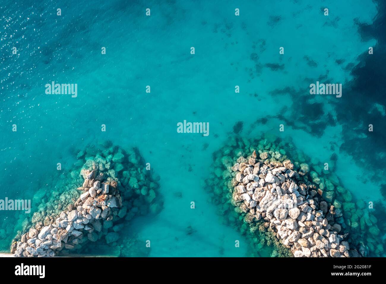 Wellenbrecher und türkisblauer Meereshintergrund, Luftdrohne von oben nach unten. Felsige Schutzmauer auf klarem, welligem Wasser, Kykladen Koufonisi isran Stockfoto