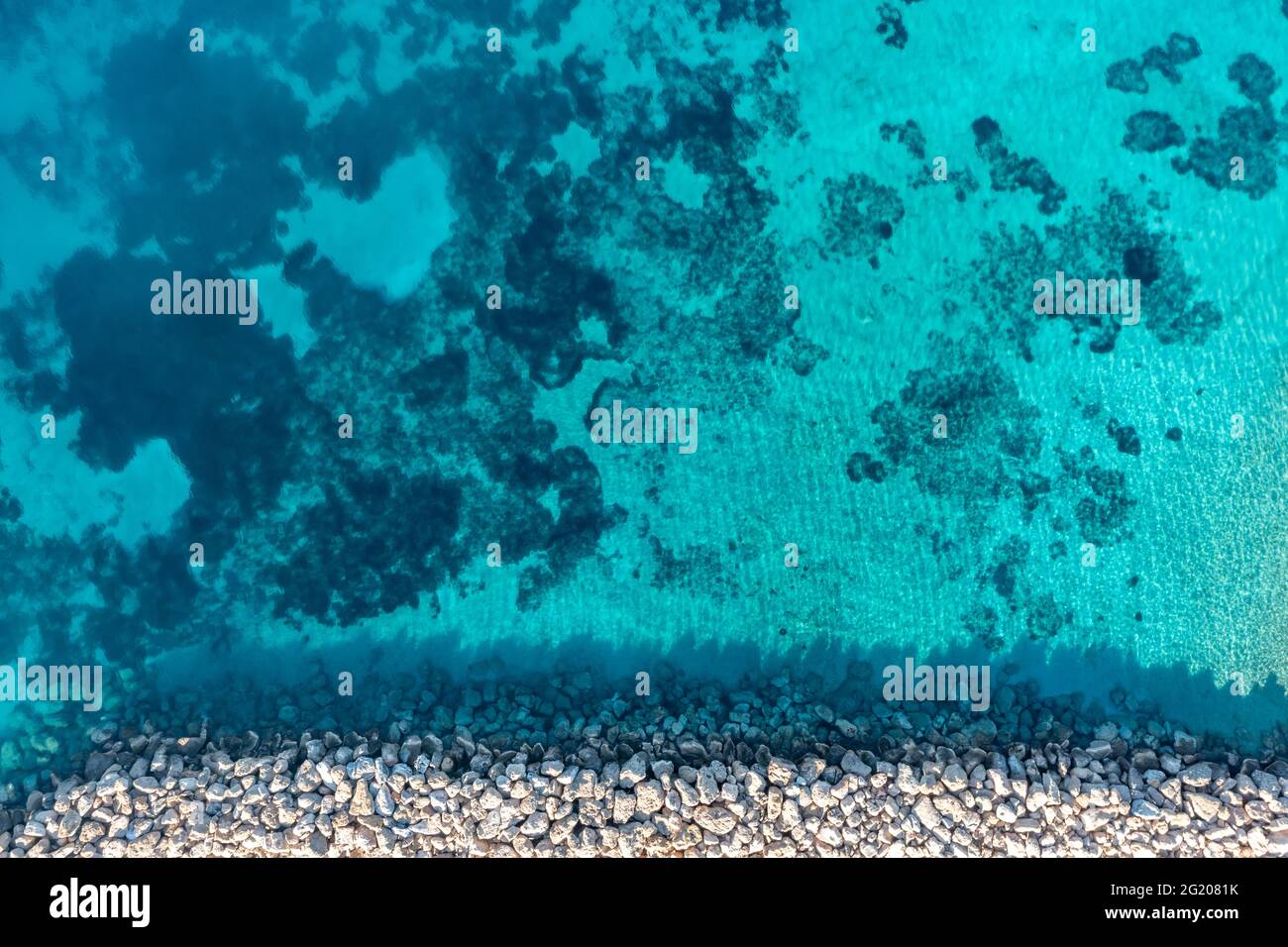 Wellenbrecher und türkisblauer Meereshintergrund, Luftdrohne von oben nach unten. Felsige Schutzmauer auf klarem, welligem Wasser, Kykladen Koufonisi isran Stockfoto