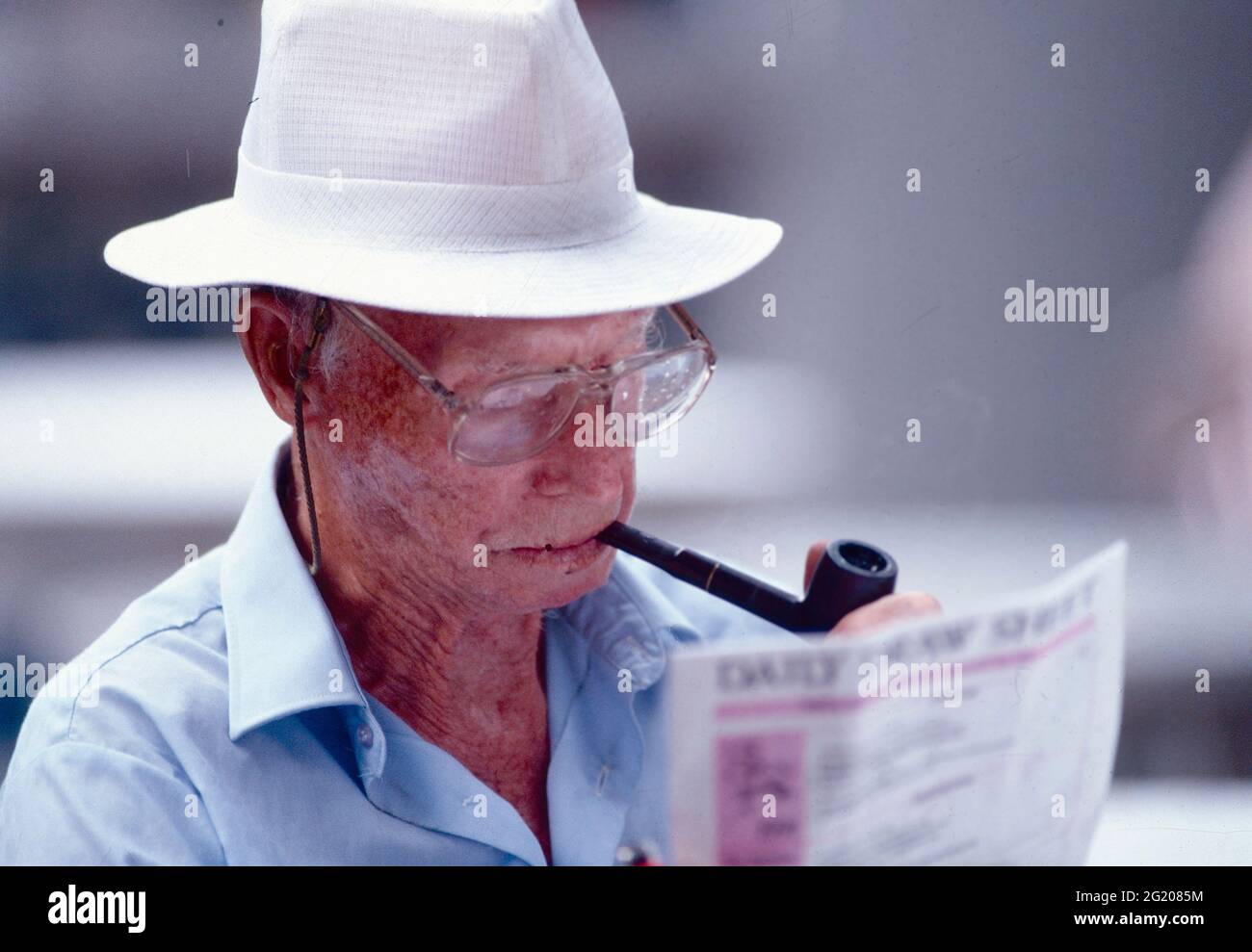 Alter Mann mit Hut beim Lesen der Zeitung, USA 1990 Stockfoto