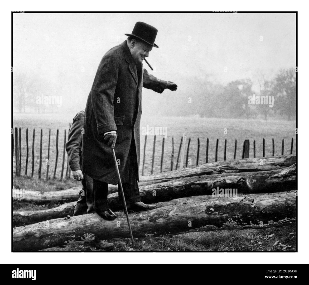 Der britische Premierminister Winston Churchill, der nach einem Besuch von Truppen im Südosten eines der fettig geneigten Baumstämme für die Infanterieausbildung aufmarschiert ist. November 1942. Stockfoto
