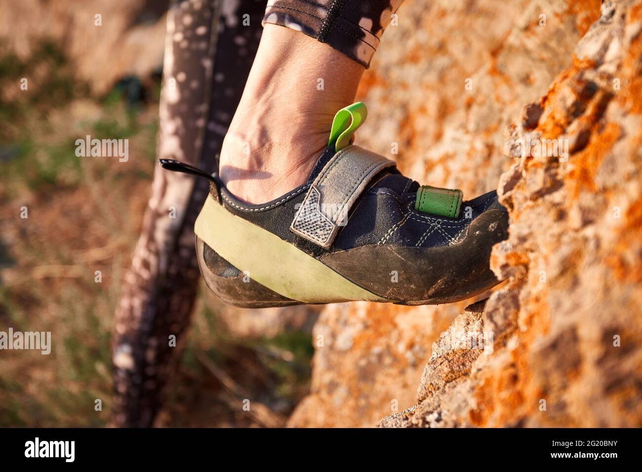 Nahaufnahme von Kletterbeinen mit Sportschuhen Griff auf dem hohen Felsen bei Sonnenuntergang in der Nähe des Flusses in Kasachstan Stockfoto