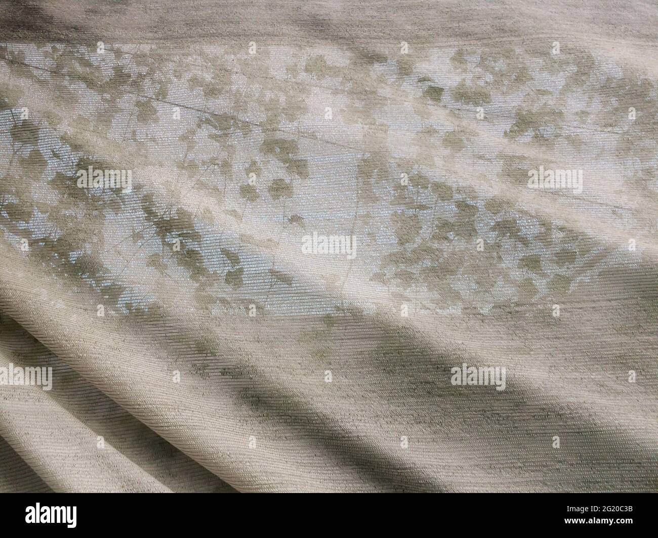Abstrakte Grabsteine in einem Gartengewächshaus, das von einem Schattierungsnetz bedeckt ist. Fokus auf Schattierungsnetz. Stockfoto
