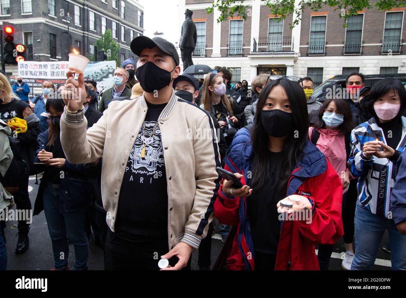 Maskierte Demonstranten versammeln sich mit Kerzen vor der chinesischen Botschaft in London, Großbritannien, zum 32. Jahrestag des Massakers vom 4. Juni auf dem Platz des Himmlischen Friedens in China. Stockfoto