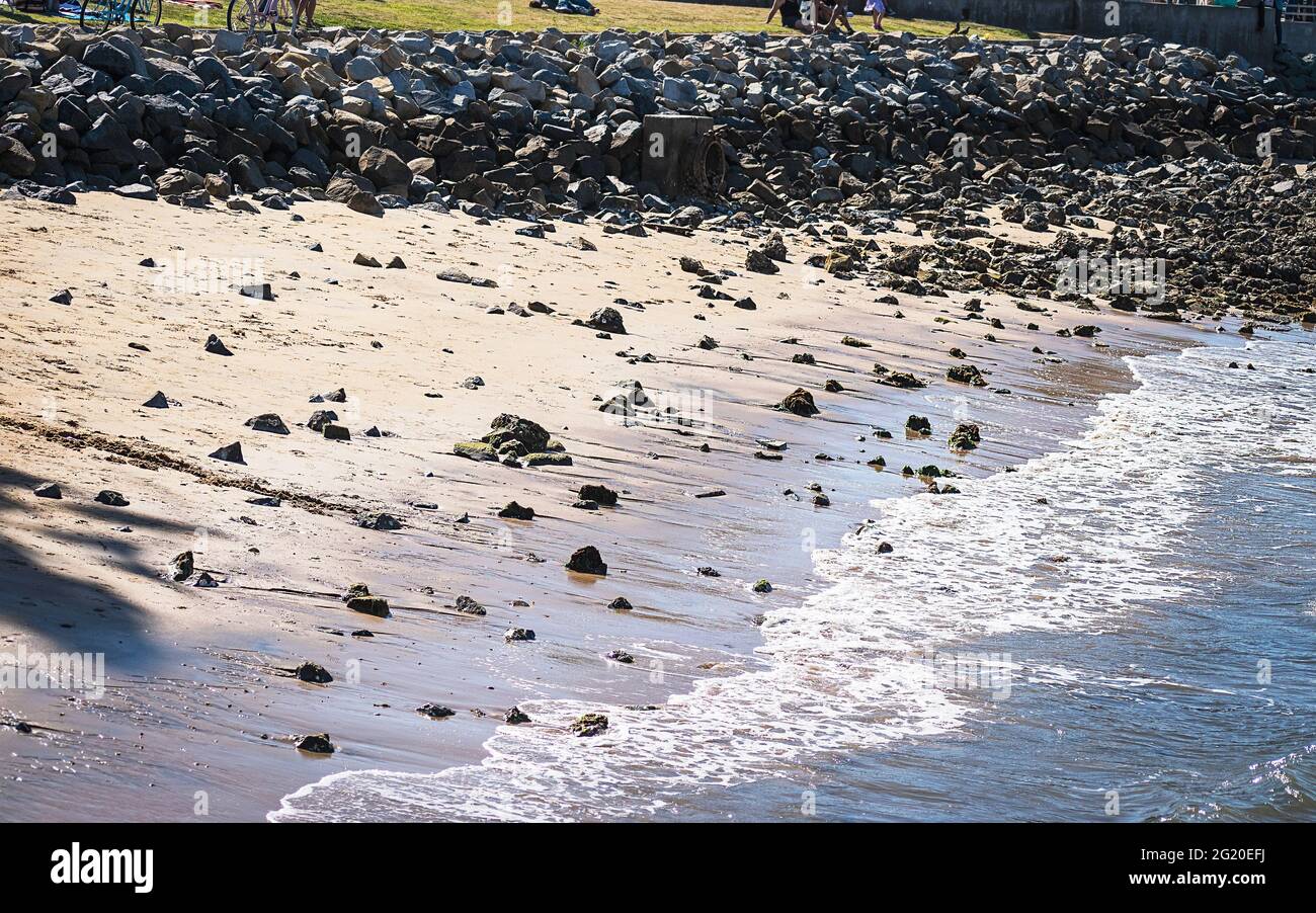 Sanfte Wellen, die friedlich den Rand eines mit Rippen verstärkten Strandabschnitts auf Coronado Island in der Nähe von San Diego in Kalifornien mit schimmernden Sonnenstrahlen umschlagen Stockfoto
