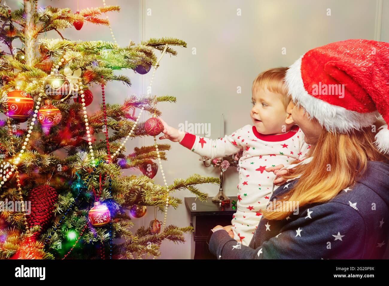Mutter und kleiner Junge setzten den Ball auf den Weihnachtsbaum Stockfoto