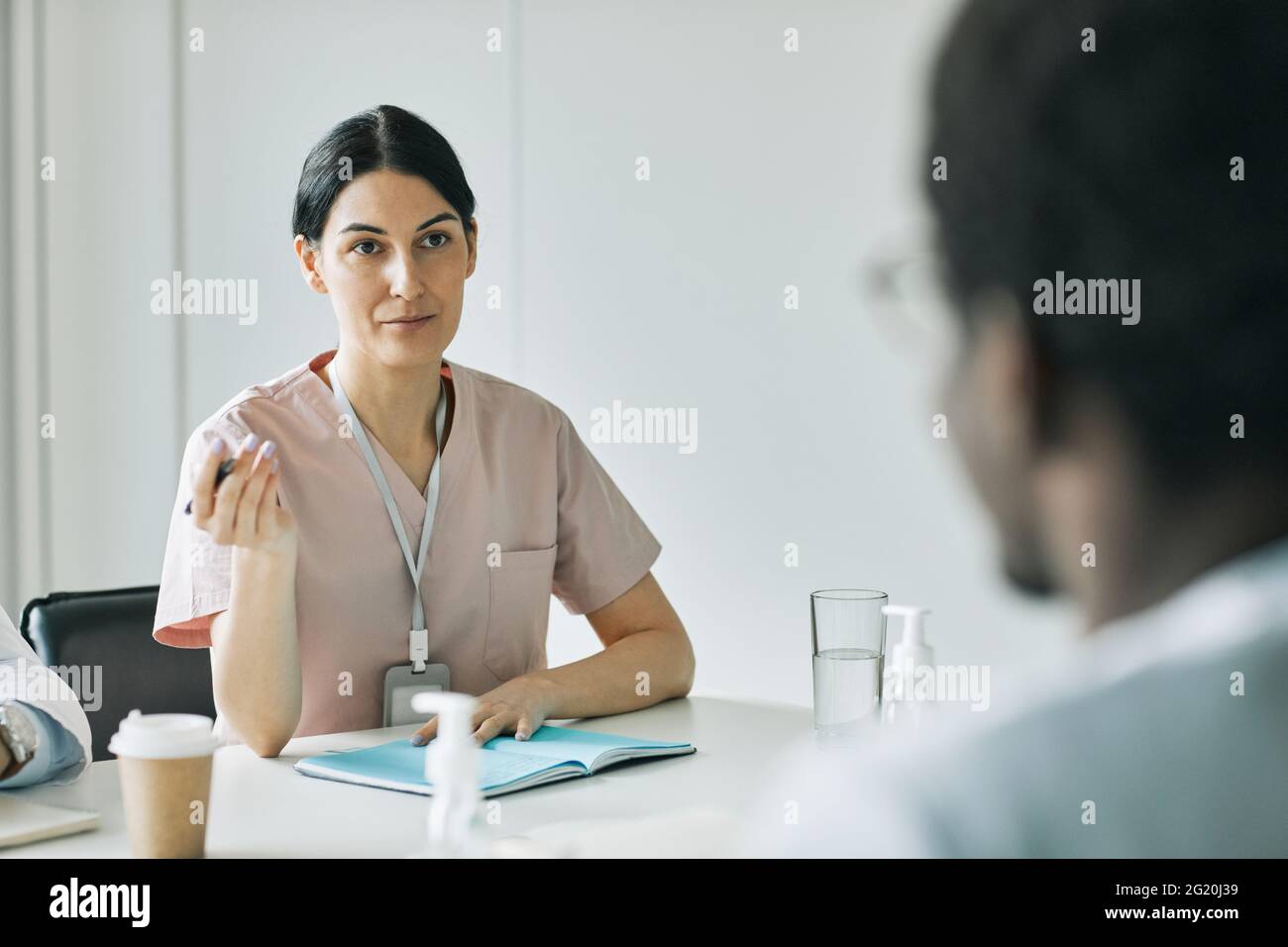 Porträt einer Ärztin, die während eines medizinischen Meetings im Konferenzraum mit Kollegen spricht, Kopierraum Stockfoto